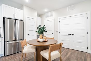 a kitchen with a stainless steel refrigerator and a table and chairs